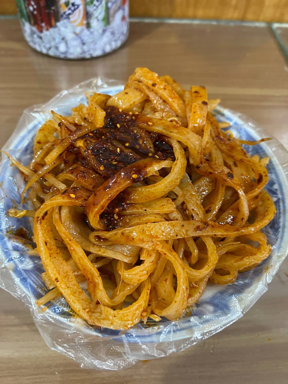 一碗调好的擀面皮，深色面皮配面筋与辣椒油